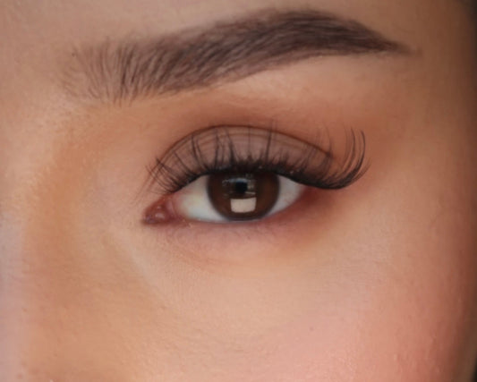 Close-up of a person's eye with long eyelashes and a gold earring.