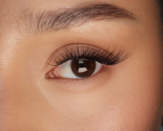 Close-up of a person's eye with long, dark eyelashes.